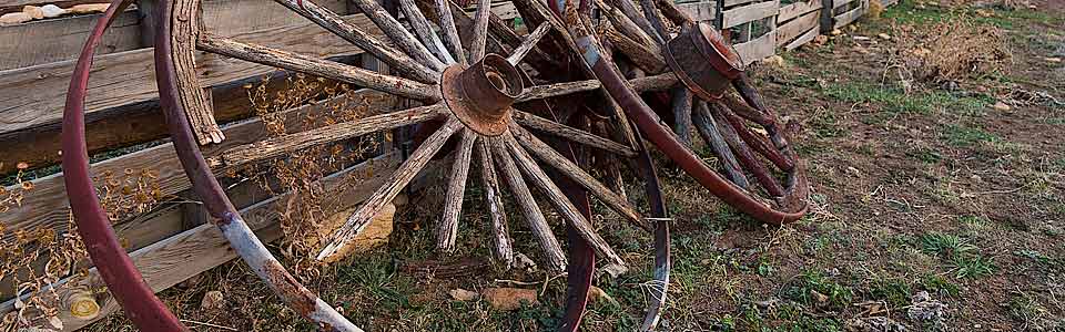 Old wagon wheels lean against a fence
